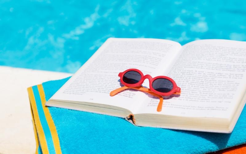 a book and sunglasses on a beach